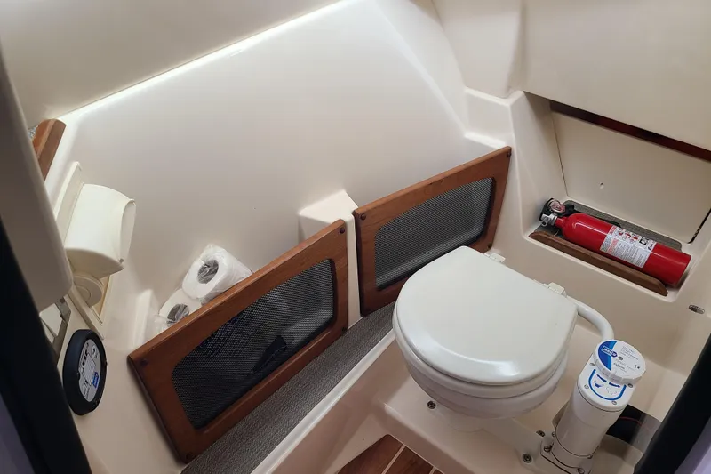 Slide: The Image of 2017 Grady-White Freedom 235 boat bathroom with toilet, fire extinguisher, and storage compartments. - 14