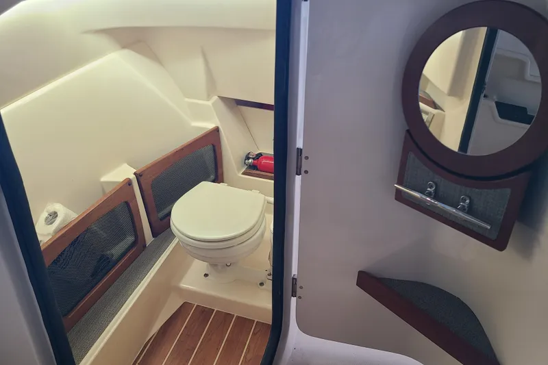 Slide: The Image of 2017 Grady-White Freedom 235 boat interior with toilet, mirror, and wooden accents. - 15