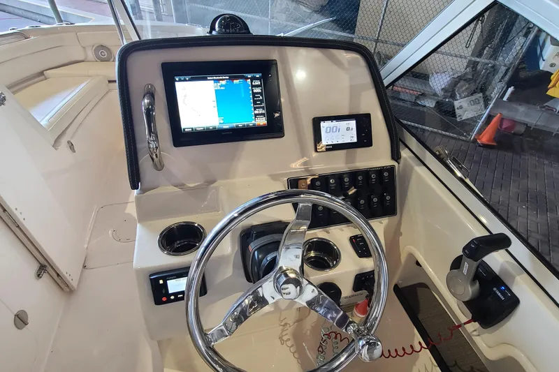 Slide: The Image of 2017 Grady-White Freedom 235 boat dashboard with steering wheel and navigation controls. - 9