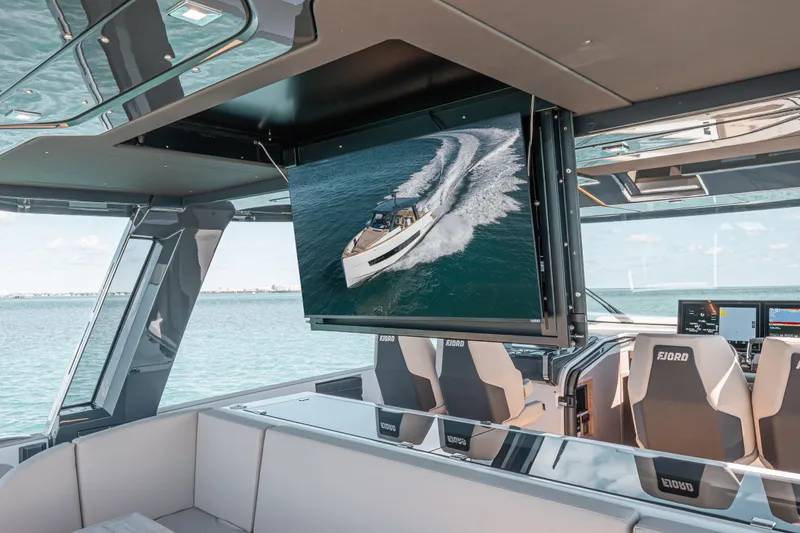 Slide: The Image of Luxurious interior of 2026 Fjord 490 SPORT yacht with modern seating and large screen display. - 12