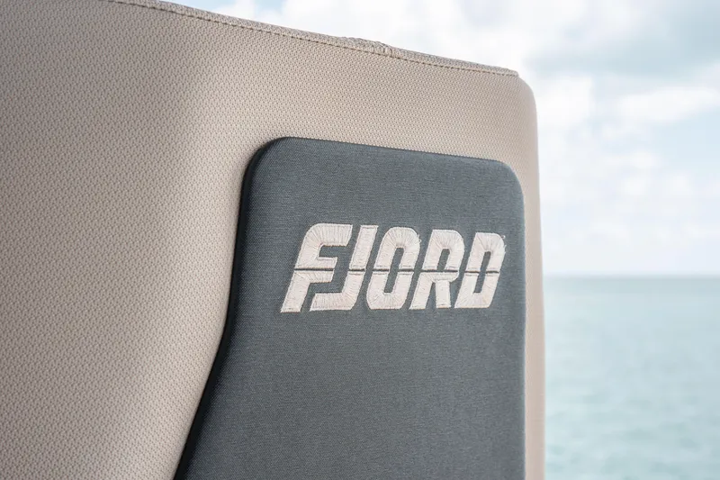 Slide: The Image of Close-up of 2026 Fjord 490 SPORT logo on boat seat with ocean background. - 16