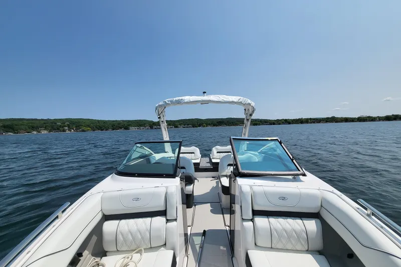 Slide: The Image of 2023 Regal LS4 boat on a serene lake under clear blue skies. - 14