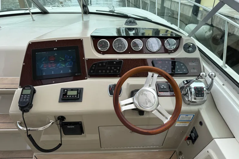 Slide: The Image of 2012 Sea Ray 370 Sundancer helm with modern controls and wooden steering wheel. - 19