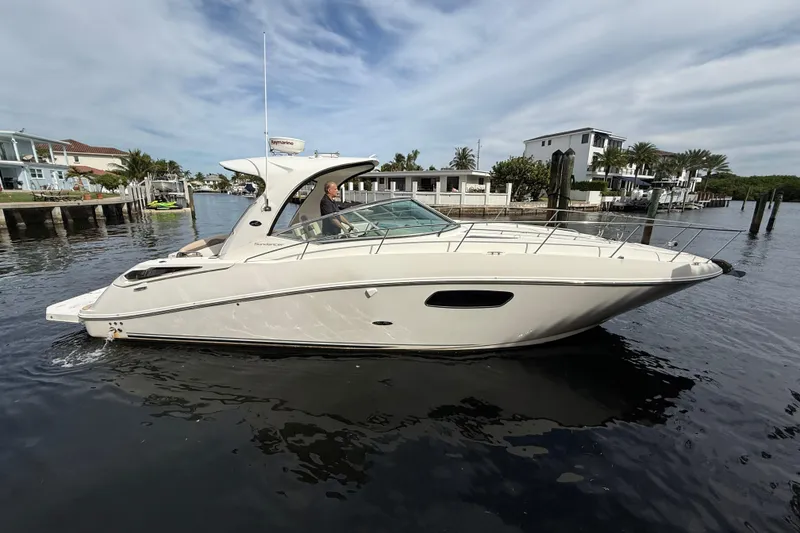 Slide: The Image of 2012 Sea Ray 370 Sundancer yacht cruising in a scenic waterfront setting. - 2