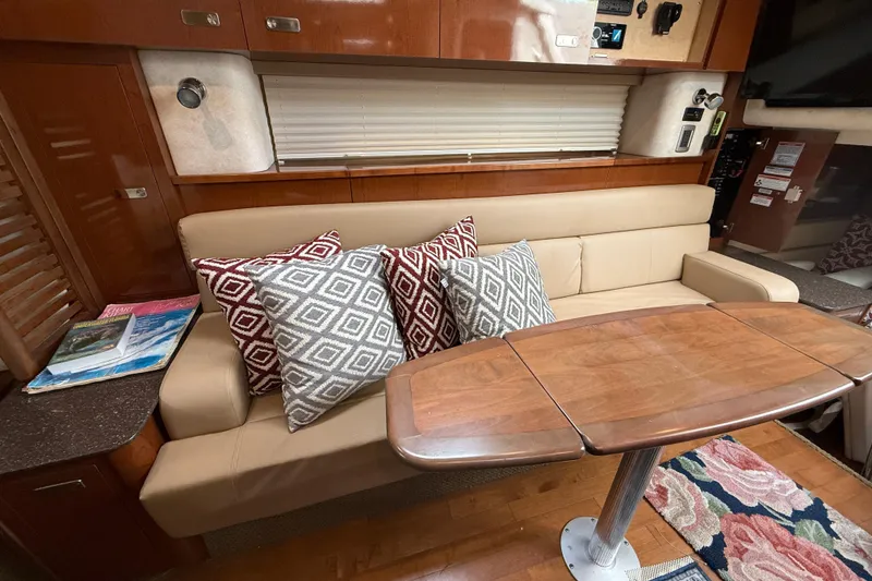 Slide: The Image of Interior of 2012 Sea Ray 370 Sundancer with beige sofa, patterned pillows, and wooden table. - 31