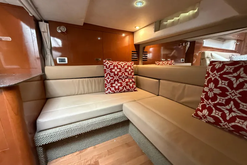 Slide: The Image of Luxurious interior of 2012 Sea Ray 370 Sundancer with beige seating and red floral pillows. - 34