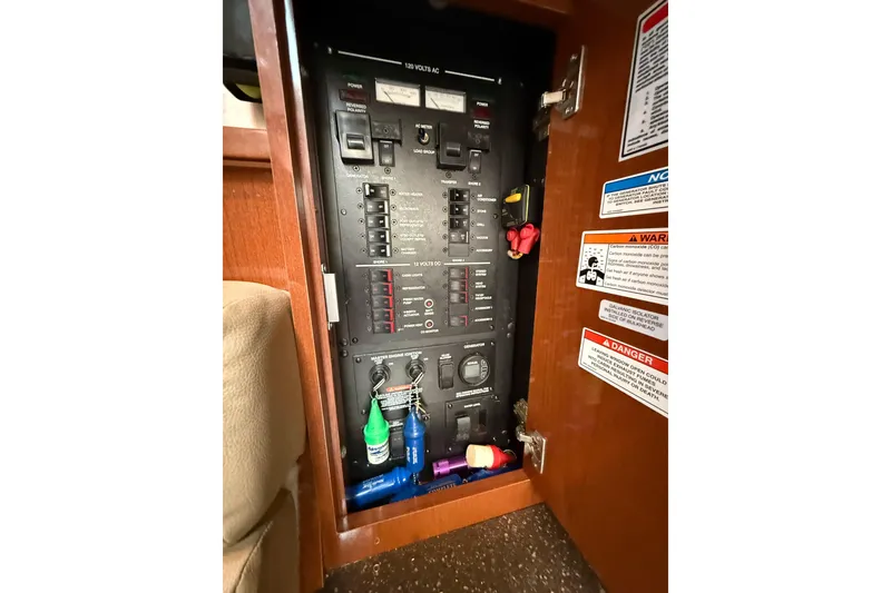 Slide: The Image of Electrical panel inside 2012 Sea Ray 370 Sundancer boat, featuring switches and warning labels. - 38