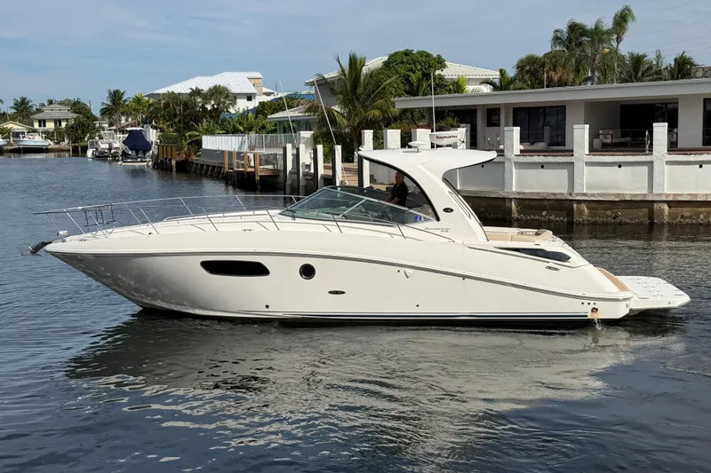 Slide: The Image of 2012 Sea Ray 370 Sundancer yacht cruising on a calm waterway near waterfront homes. - 6