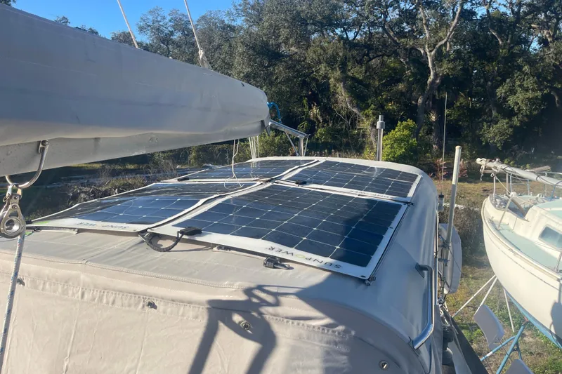 Slide: The Image of 1984 Morgan 384 sailboat with solar panels on deck, surrounded by trees. - 13