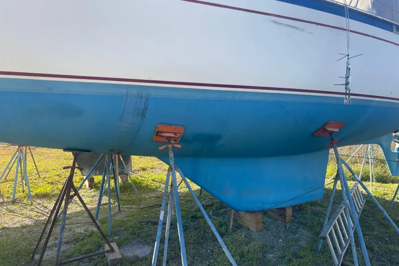 Slide: The Image of 1984 Morgan 384 sailboat on stands, blue hull, white top, outdoor setting. - 16