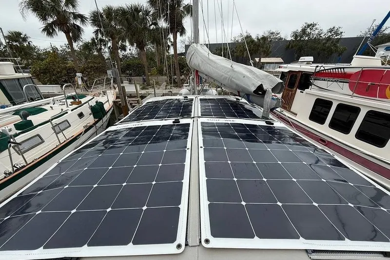Slide: The Image of 1984 Morgan 384 sailboat with solar panels on deck, docked near palm trees. - 33