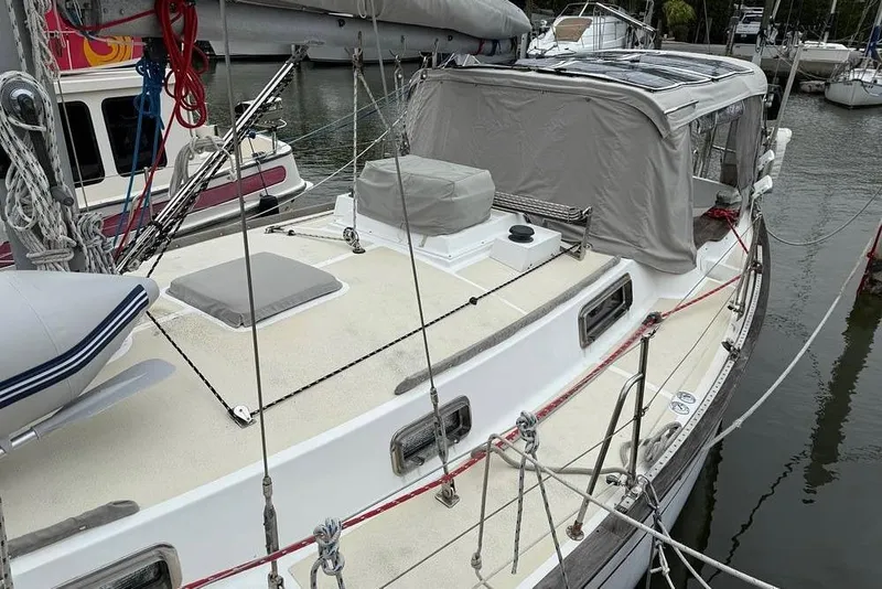 Slide: The Image of 1984 Morgan 384 sailboat docked, featuring a clean deck and covered cockpit area. - 5