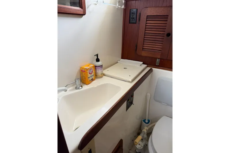 Slide: The Image of 1984 Morgan 384 yacht bathroom with sink, wooden cabinet, and cleaning supplies. - 59