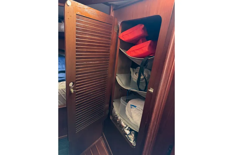 Slide: The Image of Wooden cabinet with open door, storing life jackets and gear on a 1984 Morgan 384 sailboat. - 60
