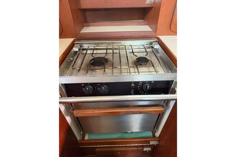 Slide: The Image of 1984 Morgan 384 yacht kitchen with a two-burner stove and oven, featuring wooden cabinetry. - 65