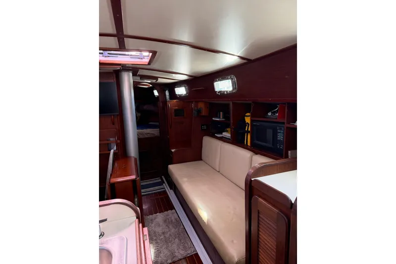 Slide: The Image of 1984 Morgan 384 yacht interior with beige seating, wooden cabinetry, and built-in microwave. - 68