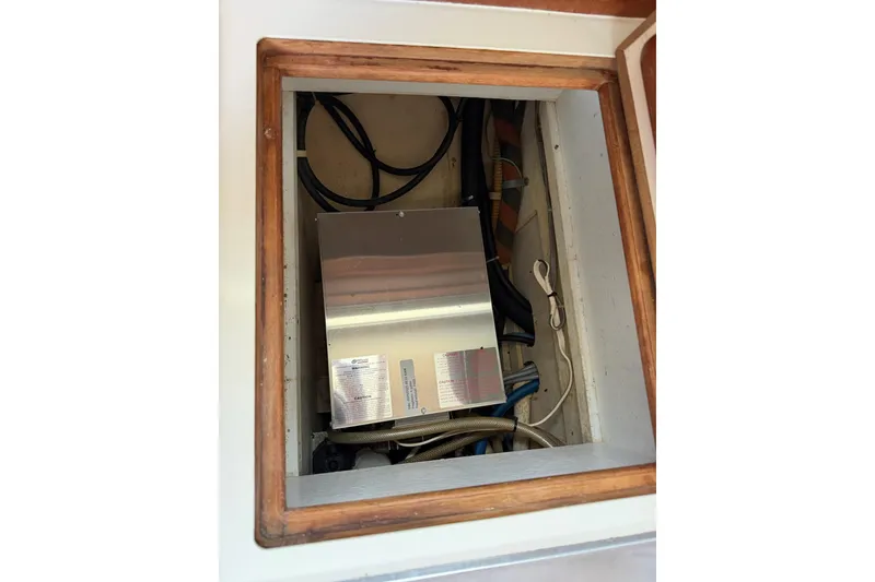 Slide: The Image of Electrical compartment of a 1984 Morgan 384 sailboat, featuring cables and a metal box. - 70