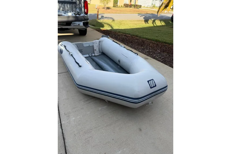 Slide: The Image of Inflatable boat on driveway, near a parked vehicle, sunny day. - 83