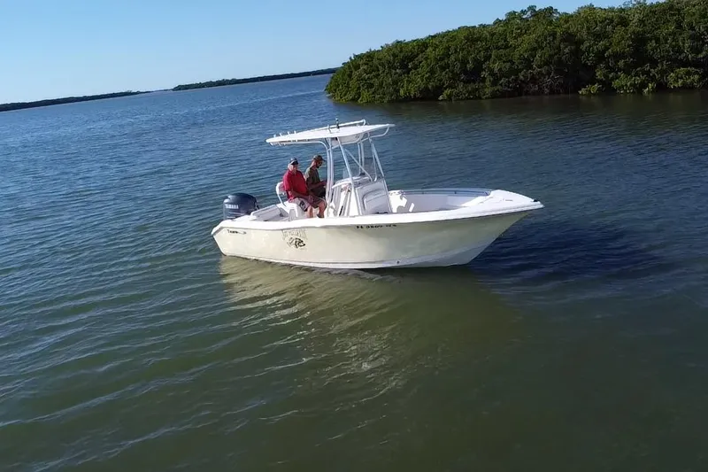 Slide: The Image of 2008 Tidewater 216 CC Adventure boat on calm water near lush green shoreline. - 19