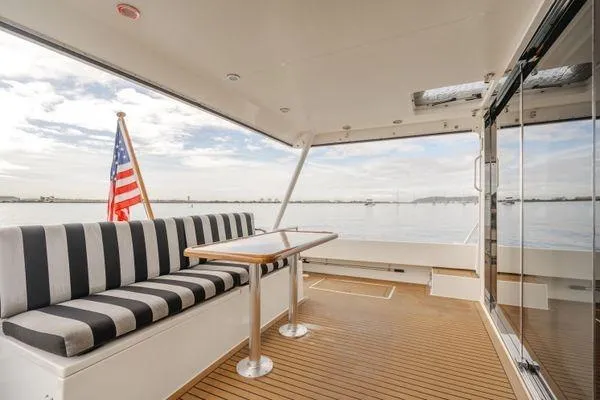 Slide: The Image of 1998 Pacific Mariner 65 yacht deck with striped seating and American flag. - 26