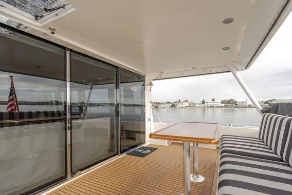 Slide: The Image of 1998 Pacific Mariner 65 yacht deck with striped seating and wooden table, overlooking calm waters. - 27