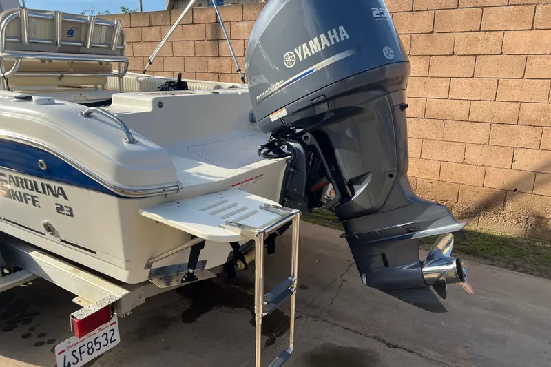 Slide: The Image of 2016 Carolina Skiff 23 Ultra Elite with Yamaha outboard motor, parked near a brick wall. - 2