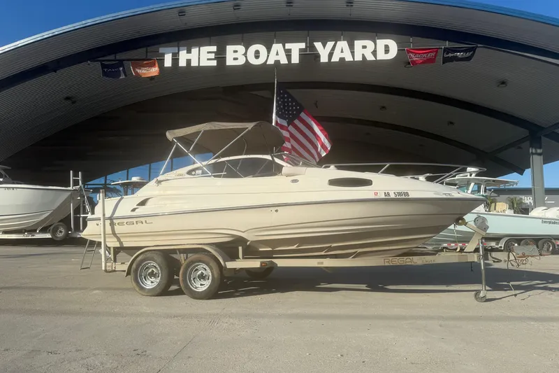 Slide: The Image of 1998 Regal 2250 LSC boat on trailer at The Boat Yard, displaying American flag. - 1