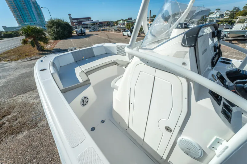 Slide: The Image of 2020 Twin Vee 240 GFX CC boat interior with seating and console, parked near a road. - 30