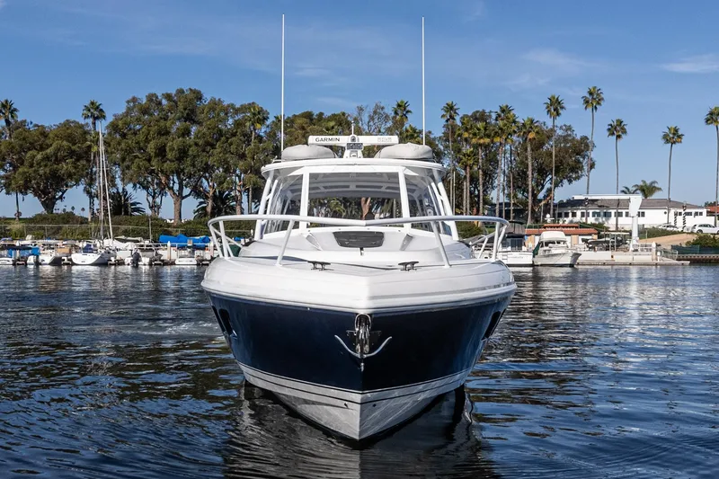 Slide: The Image of 2016 Intrepid 400 Cuddy boat on calm water, surrounded by trees and marina. - 14