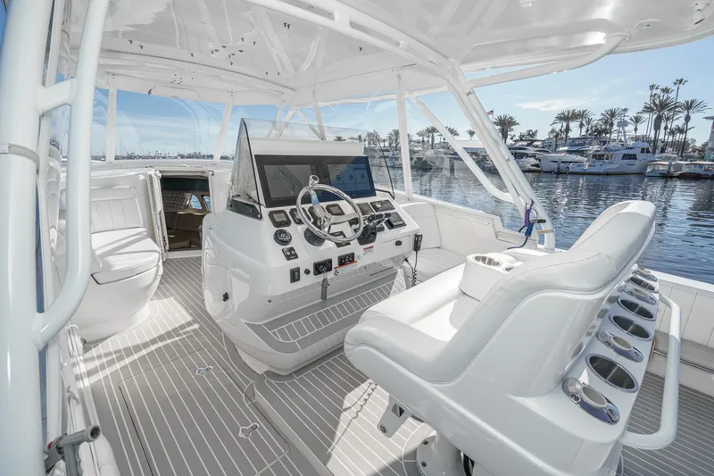 Slide: The Image of 2016 Intrepid 400 Cuddy boat interior with helm, luxurious seating, and marina view. - 32