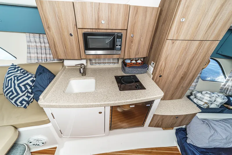 Slide: The Image of 2016 Intrepid 400 Cuddy interior with kitchenette, featuring sink, microwave, and stove. - 54
