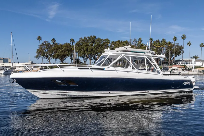 Slide: The Image of 2016 Intrepid 400 Cuddy boat on calm water, surrounded by trees and buildings. - 8