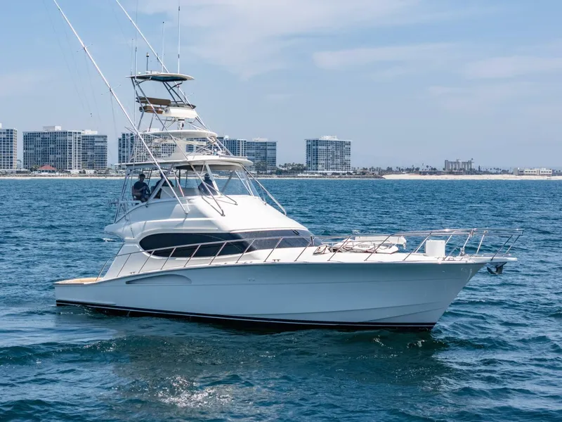 The Image of 2004 Hatteras 54 Convertible yacht cruising on the ocean with city skyline in background. - 1