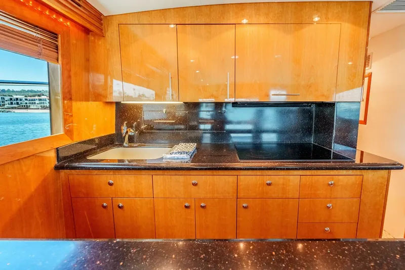 Slide: The Image of Luxurious kitchen interior of 2004 Hatteras 54 Convertible yacht with wood cabinetry and black countertops. - 14