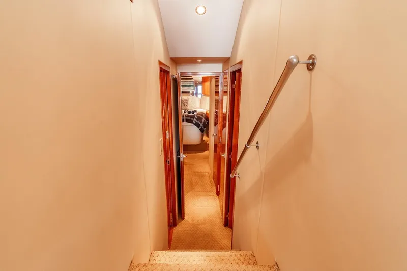 Slide: The Image of Interior hallway of 2004 Hatteras 54 Convertible yacht, featuring carpeted flooring and wooden doors. - 16