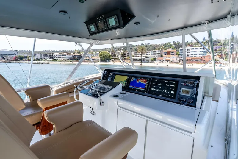 Slide: The Image of Helm of 2004 Hatteras 54 Convertible yacht with modern navigation equipment and coastal view. - 34