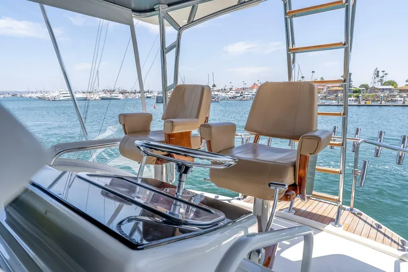 Slide: The Image of Luxury helm chairs on a 2004 Hatteras 54 Convertible yacht, overlooking a marina. - 37