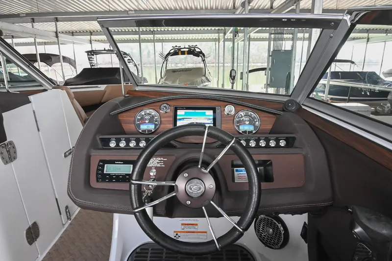 Slide: The Image of 2015 Cobalt R7 boat dashboard with steering wheel and control panel in marina setting. - 27