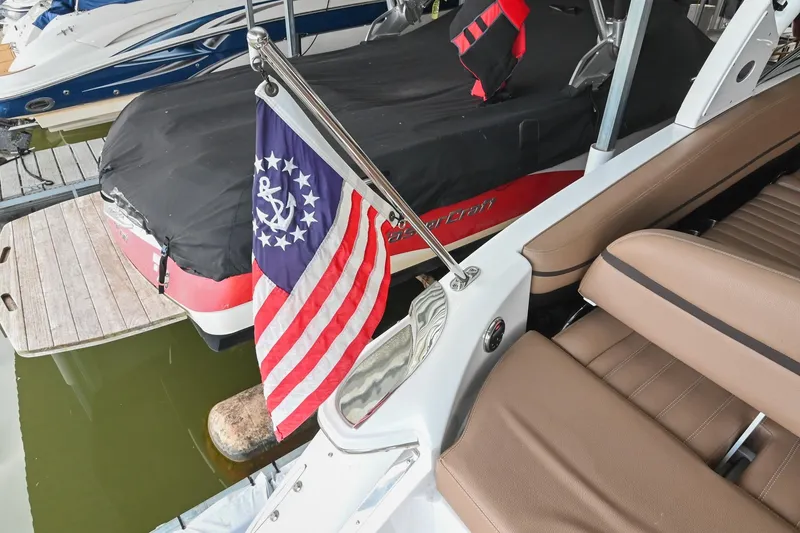 Slide: The Image of 2015 Cobalt R7 boat with American flag, docked near covered vessel. - 8