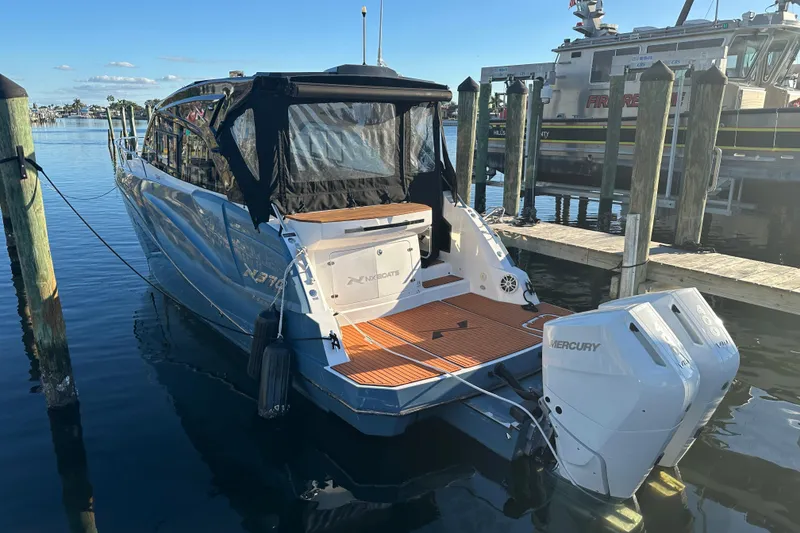 Slide: The Image of 2025 NX Boats 370 docked, featuring dual Mercury outboard engines and sleek design. - 0