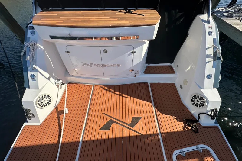 Slide: The Image of 2025 NX Boats 370 deck with wood finish and branded logo. - 11