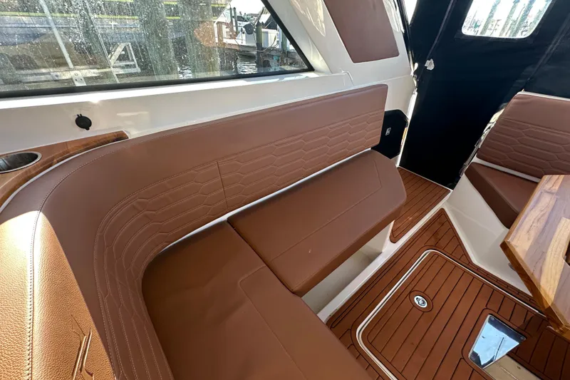 Slide: The Image of 2025 NX Boats 370 interior with brown leather seating and wooden flooring. - 113