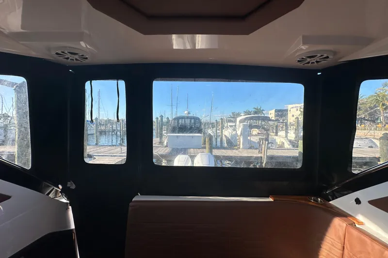 Slide: The Image of Interior view from NX Boats 370, 2025 model, overlooking marina with docked boats. - 115