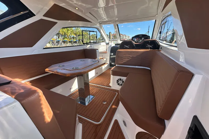 Slide: The Image of Interior of 2025 NX Boats 370, featuring brown seating and a wooden table. - 15