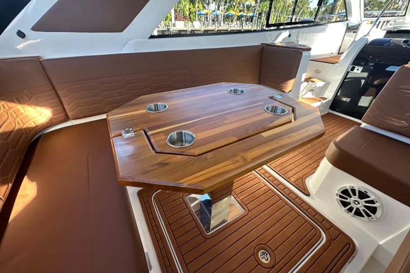 Slide: The Image of Luxurious interior of 2025 NX Boats 370 with wooden table and brown seating. - 16