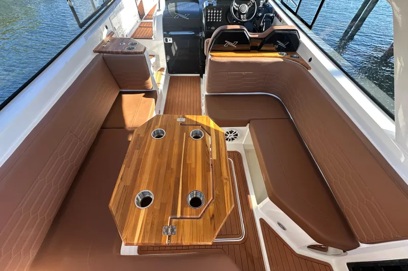 Slide: The Image of 2025 NX Boats 370 interior with brown seating and wooden table on water. - 20