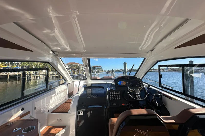 Slide: The Image of Interior view of 2025 NX Boats 370, showcasing helm and seating with marina backdrop. - 21