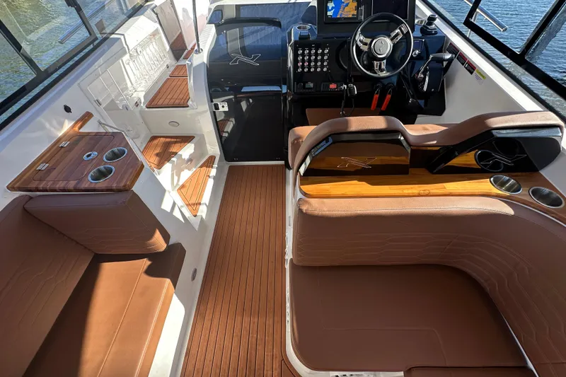 Slide: The Image of 2025 NX Boats 370 interior with brown leather seating, modern helm, and wooden accents. - 23