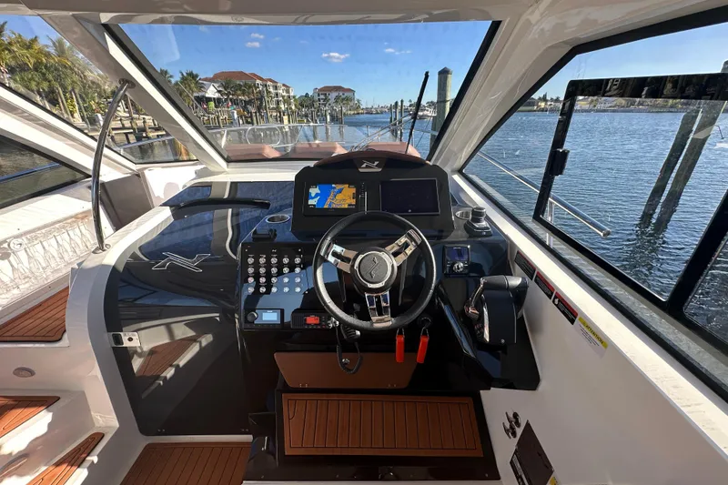 Slide: The Image of Interior view of 2025 NX Boats 370 helm with modern controls and waterfront scenery. - 27