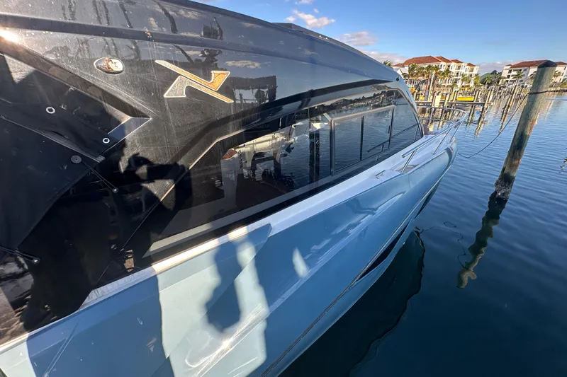 Slide: The Image of 2025 NX Boats 370 docked, reflecting on calm water with clear blue sky. - 4